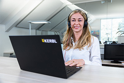 Eine Kerbl Mitarbeiterin mit Headset und Laptop lächelt freundlich