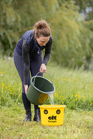 Eine Landwirtin füllt Wasser in die mit Lockstoff befüllte cit Fliegenfalle FlyCage6